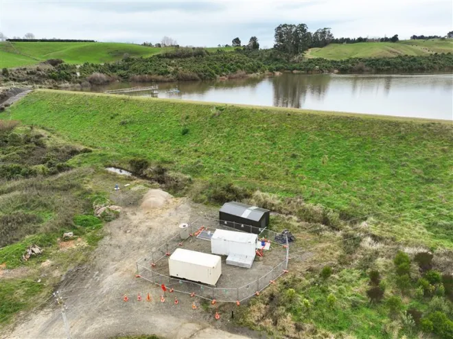 A aerial shot of the Tutaenui Reservoir in the background and the new bore and trial treatment equipment in the forground. The equipment is located in two shipping containers and surrounded by security fencing.